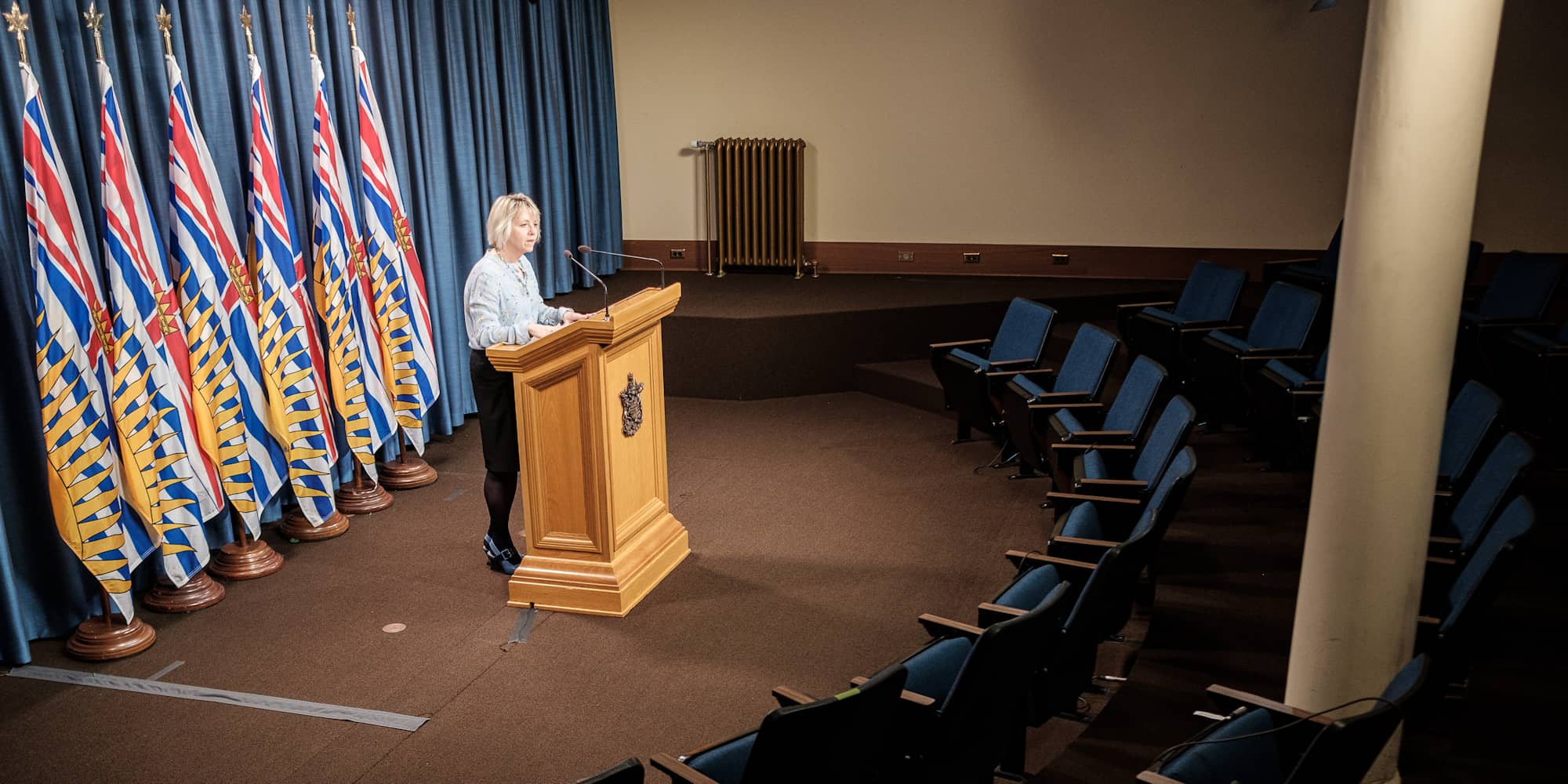 Addressing an auditorium left empty by social distancing requirements, provincial medical officer of health Bonnie Henry provides a COVID-19 update on March 25, 2020 (BC Ministry of Health).