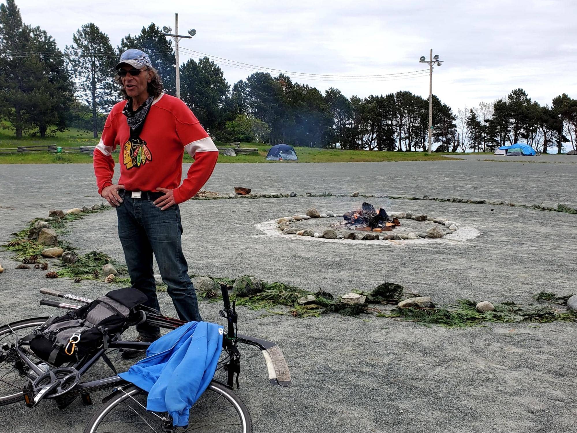 Camper Sandy Fisher stands beside a fire lit as a symbol of resistance in Beacon Hill Park. Photo: Emily Vance / Capital Daily
