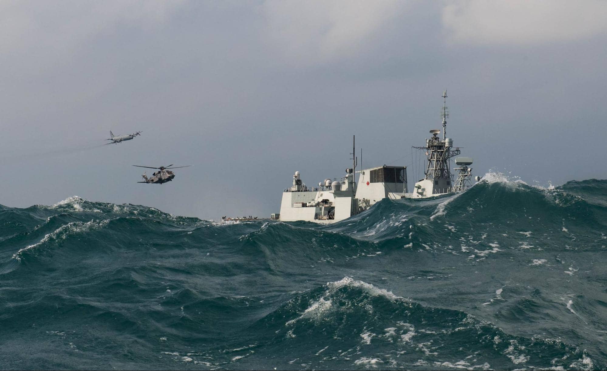 A CH-148 Cyclone helicopter and a CP-140 Aurora maritime patrol aircraft fly over HMCS WINNIPEG as part of a photo exercise in the Asia-Pacific Region during Operation NEON, November 15, 2020. Photo credit: Sailor 1st Class Valerie LeClair, MARPAC Imaging Services