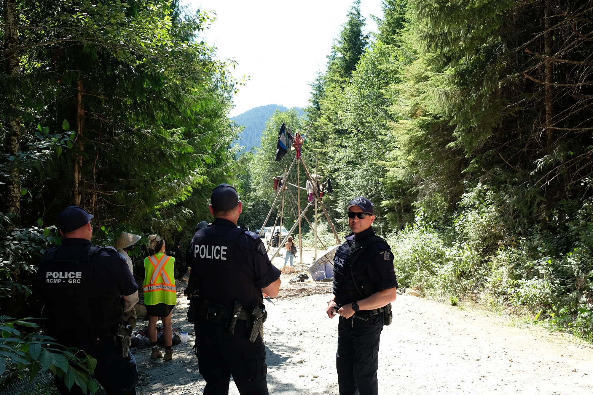 Police kept watch around people who had locked themselves into hard blocks at a blockade called Waterfall Camp in the summer. Photo: Zoë Ducklow / Capital Daily