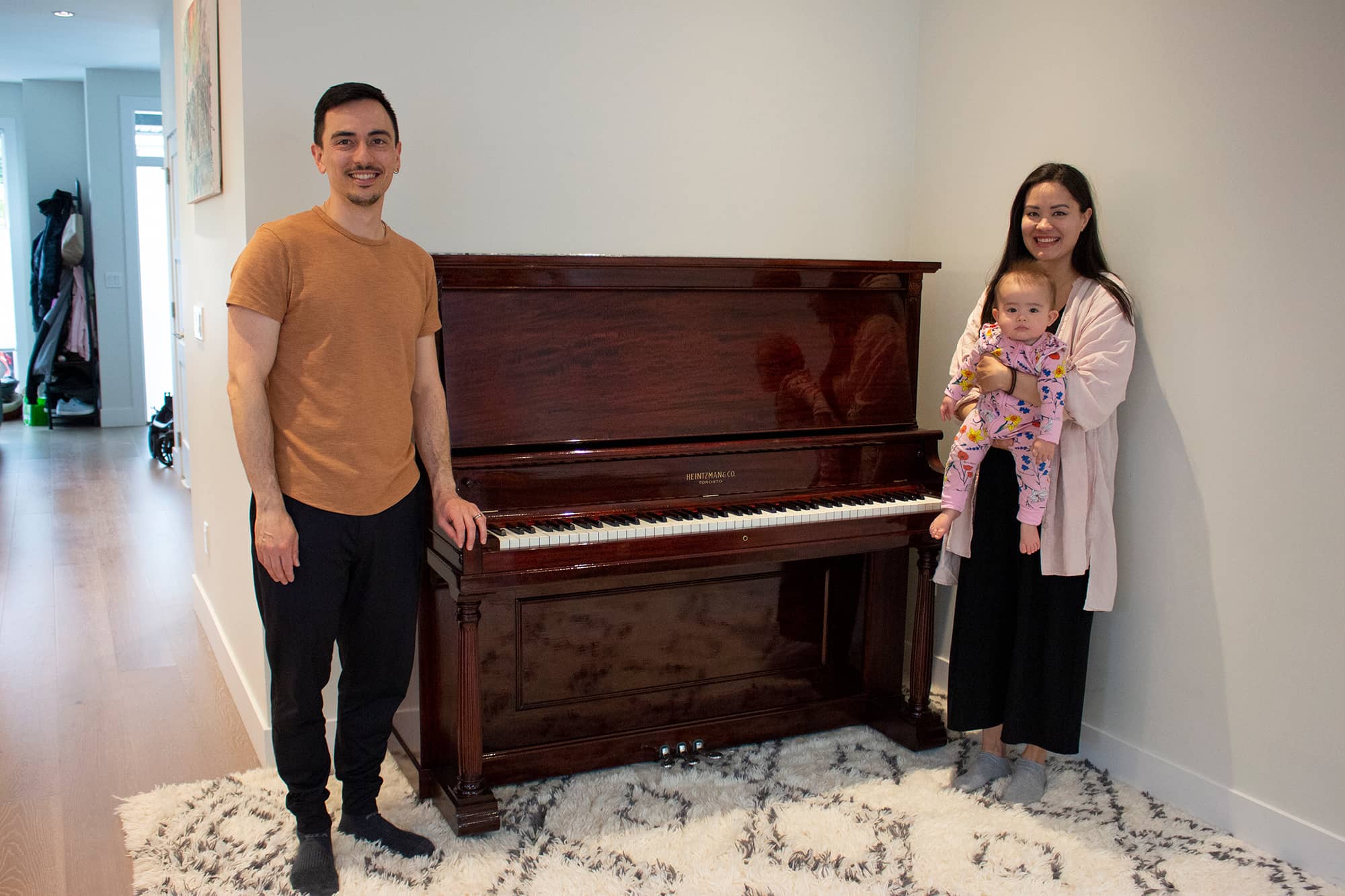 Dillon and Lisa Takata stand with their youngest daughter, Kana, in front of the piano that belonged to Dillon's great aunt Toshie. Photo: Jolene Rudisuela / Capital Daily