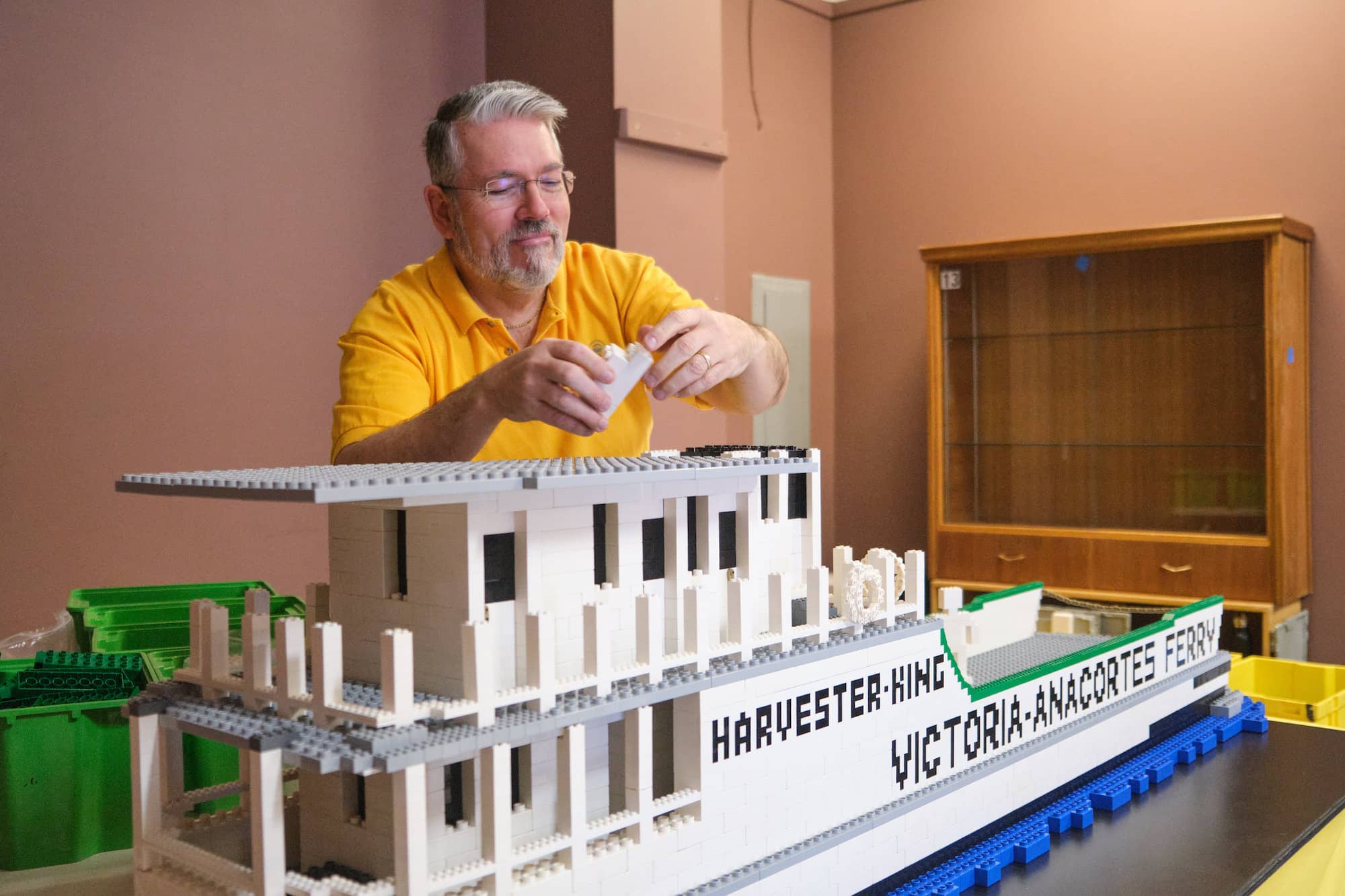 Robin Sather puts together a piece of the roof for the Lego replica of the Harvester King, the first ferry that linked Sidney to Anacortes. Photo: Michael John Lo / Capital Daily