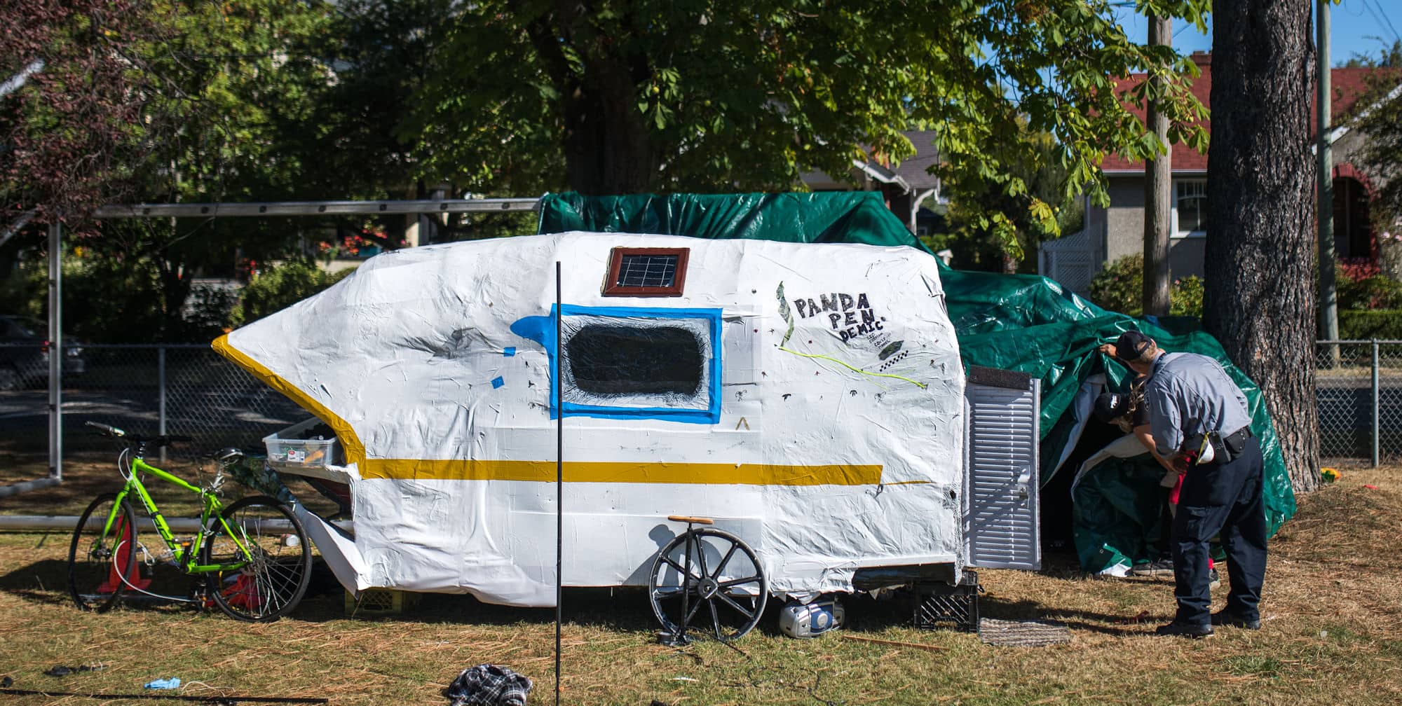 In this September 15 photo, Central Park tenter Fred Mayers talks with a bylaw officer who has requested he removes his tarps (Credit: James MacDonald for Capital Daily).