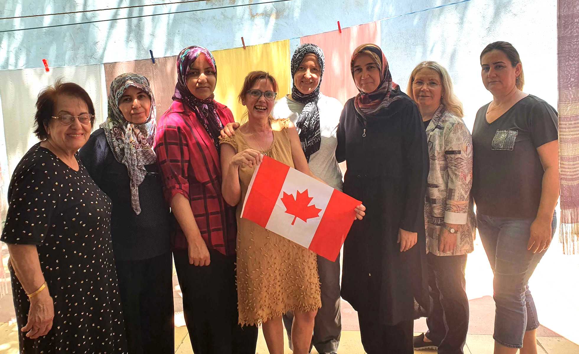 Ayca Tanyer, holding a Canadian flag, poses for a photo with workers that have been helped by the Council of Turkish Women. Tanyer is one of many business owners attending the inaugural Colourful Business Expo on Saturday.