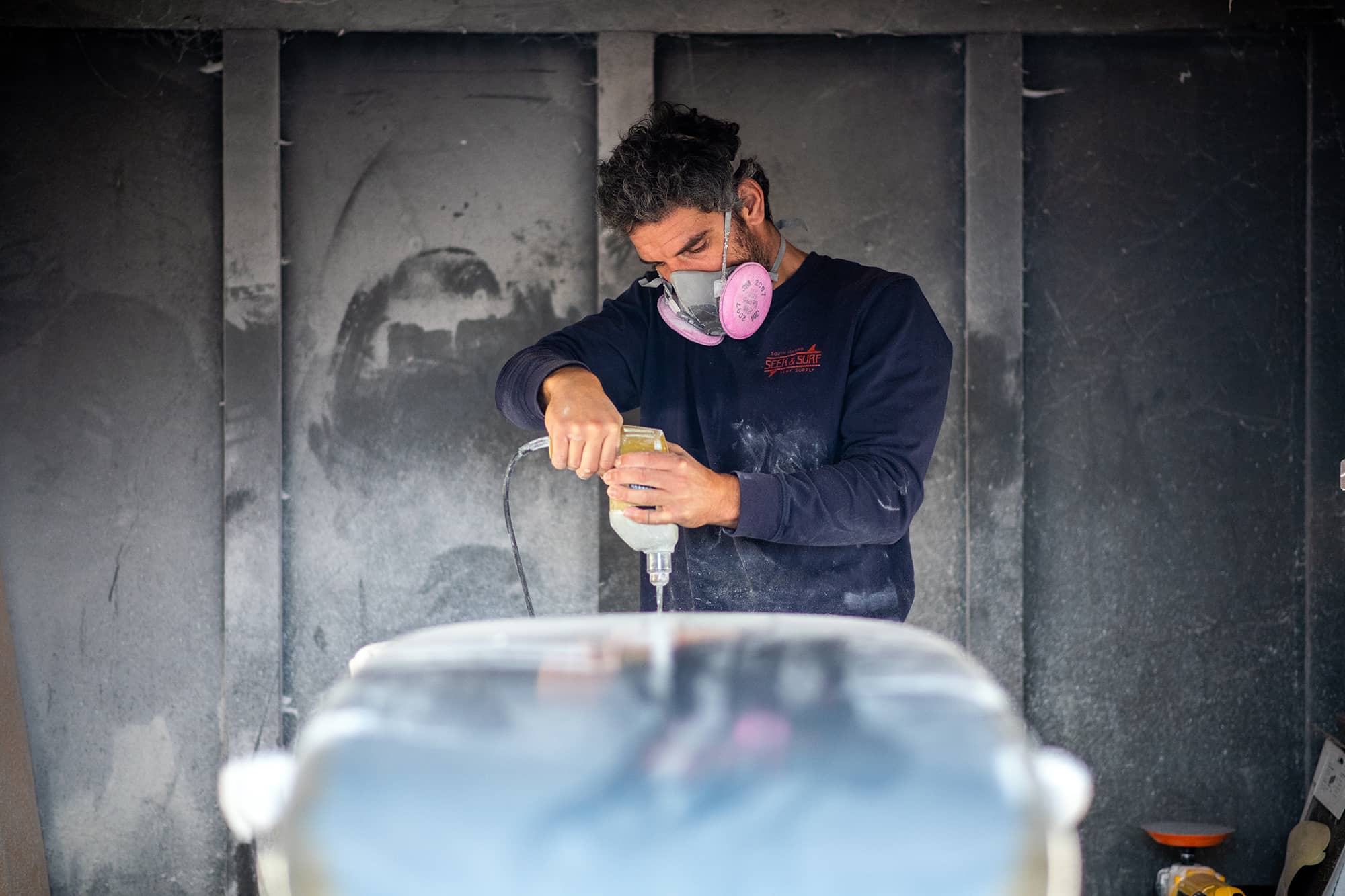Surfboard shaper Jorge Elias drills holes for fins in an almost completed long board in his Sooke workshop. Photo: James MacDonald / Capital Daily