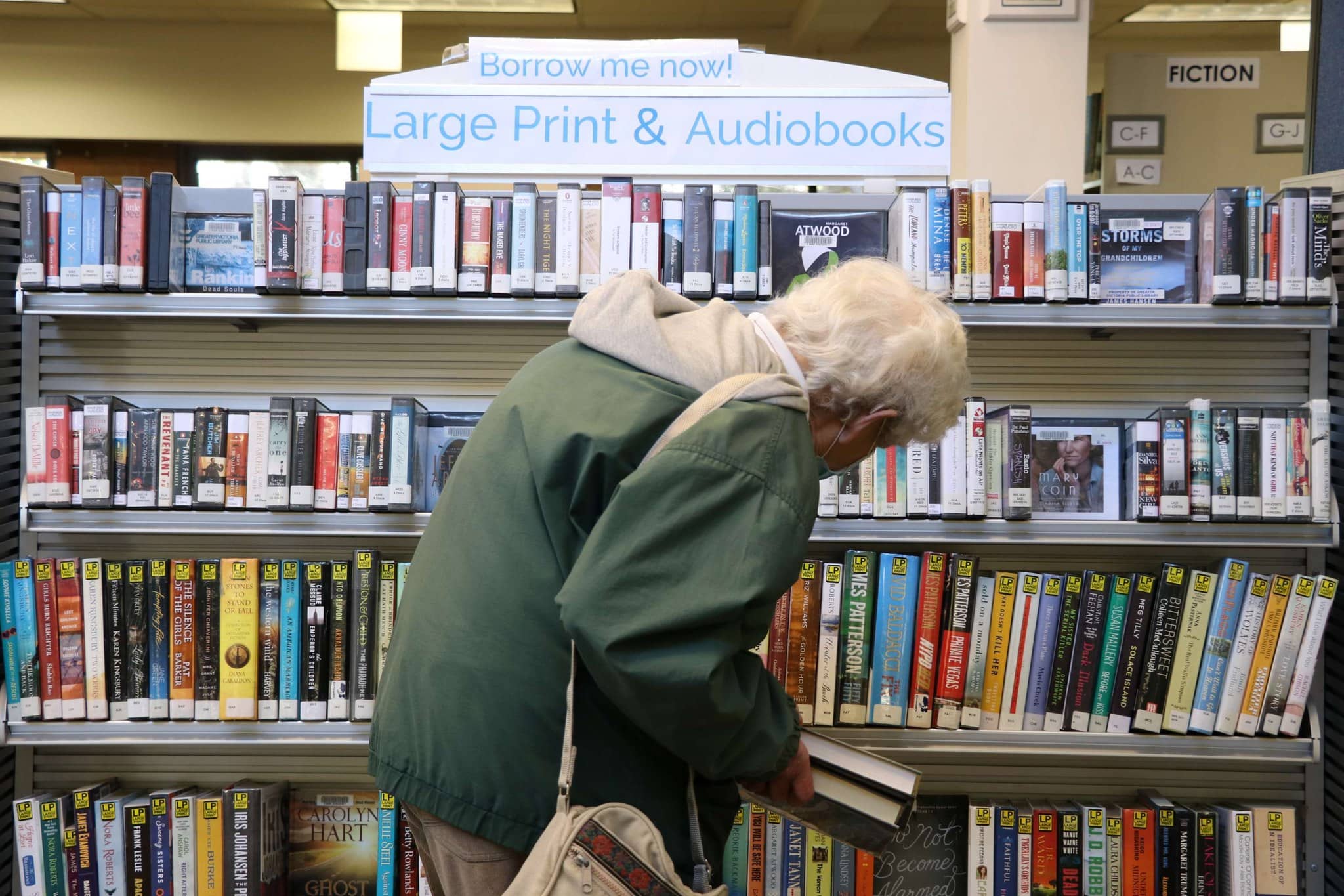 A person peruses the Large Print section at a GVPL branch. Photo: GVPL / Facebook
